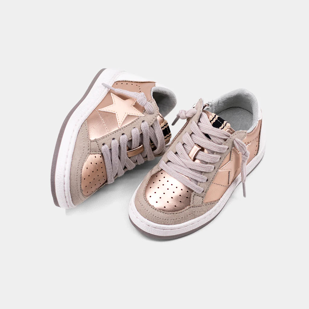 Pair of rose gold sneakers with star details on a light gray background